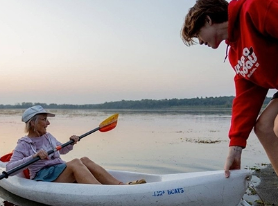 employee helping woman in kayak